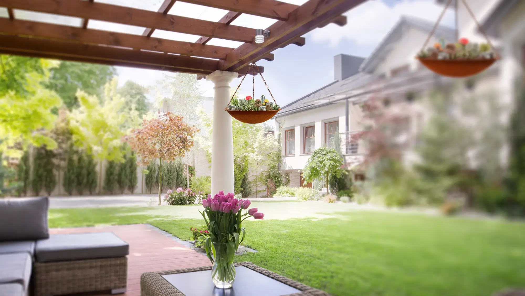 Outdoor seating area under a wooden pergola with hanging planters and a garden view in a modern backyard